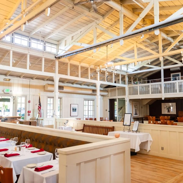 Spacious dining room at MacArthur Park Restaurant with white tables, red napkins, and a high vaulted ceiling.