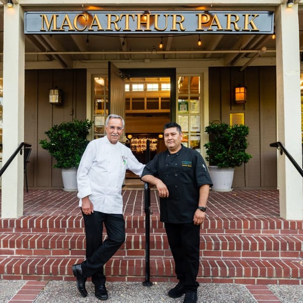 Two chefs, one older and one younger, stand proudly in front of MacArthur Park Restaurant.