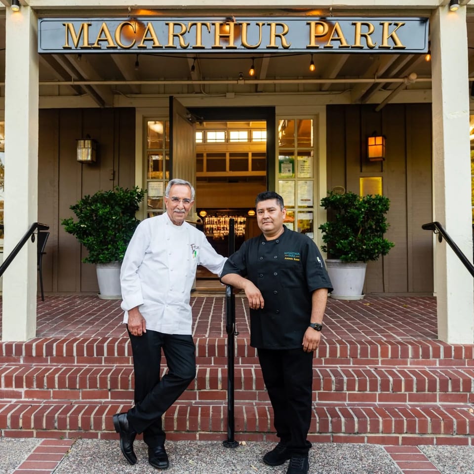 Two chefs, one older and one younger, stand proudly in front of MacArthur Park Restaurant.