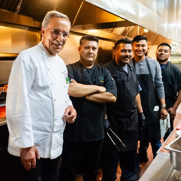 Five MacArthur Park Restaurant and Bar chefs, including one older chef, smiling in a kitchen.