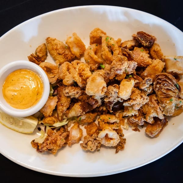 Crispy fried calamari and artichoke hearts with a side of creamy dipping sauce and lemon.