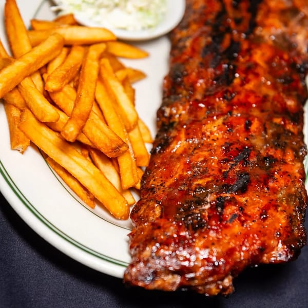 A plate of MacArthur Park Restaurant's BBQ ribs with french fries and coleslaw.